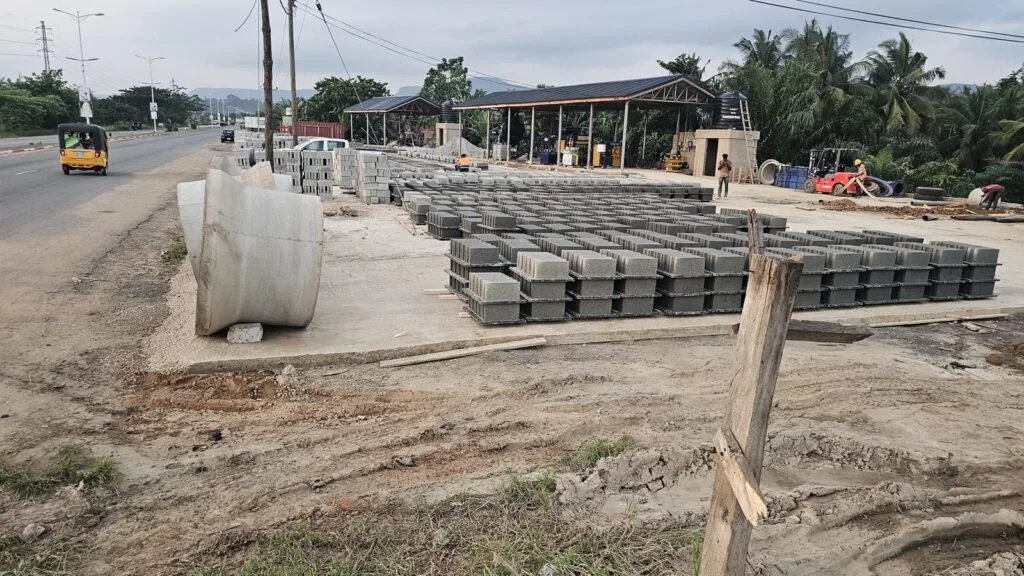 Rows of concrete blocks curing on pallets at the Quasi Group production yard, with concrete pipes in the foreground